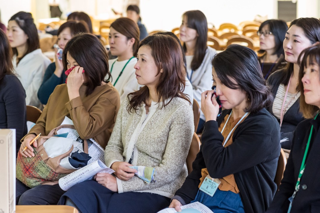 Group of Japanese mothers in a seminar room watching emotional videos as part of a tears therapy session led by tear therapist Hidefumi Yoshida.