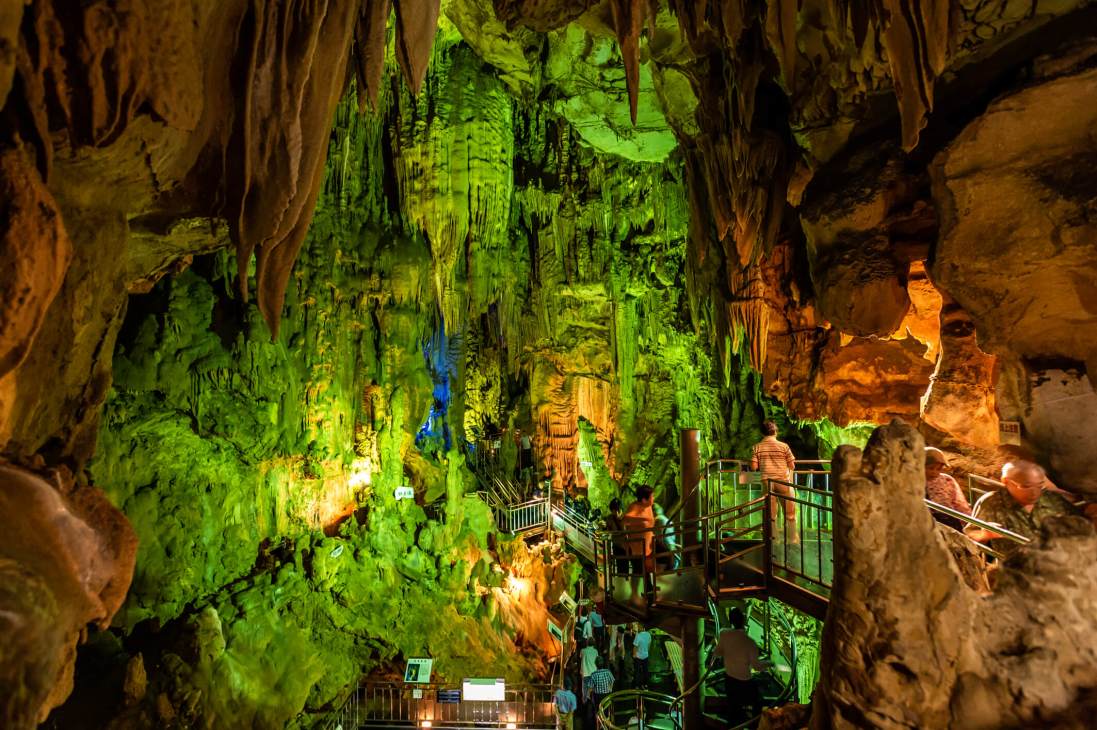 Abukuma Cave in Fukushima with illuminated stalactites, limestone formations, and visitors on metal walkways.