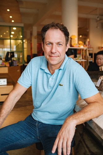 Man in light blue polo shirt sitting at a table in a café