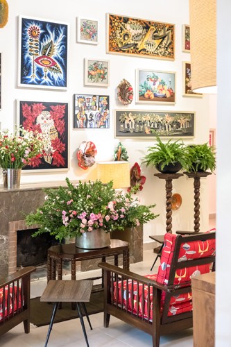 Hotel interior with gallery wall of framed artwork, plants, and red patterned chair