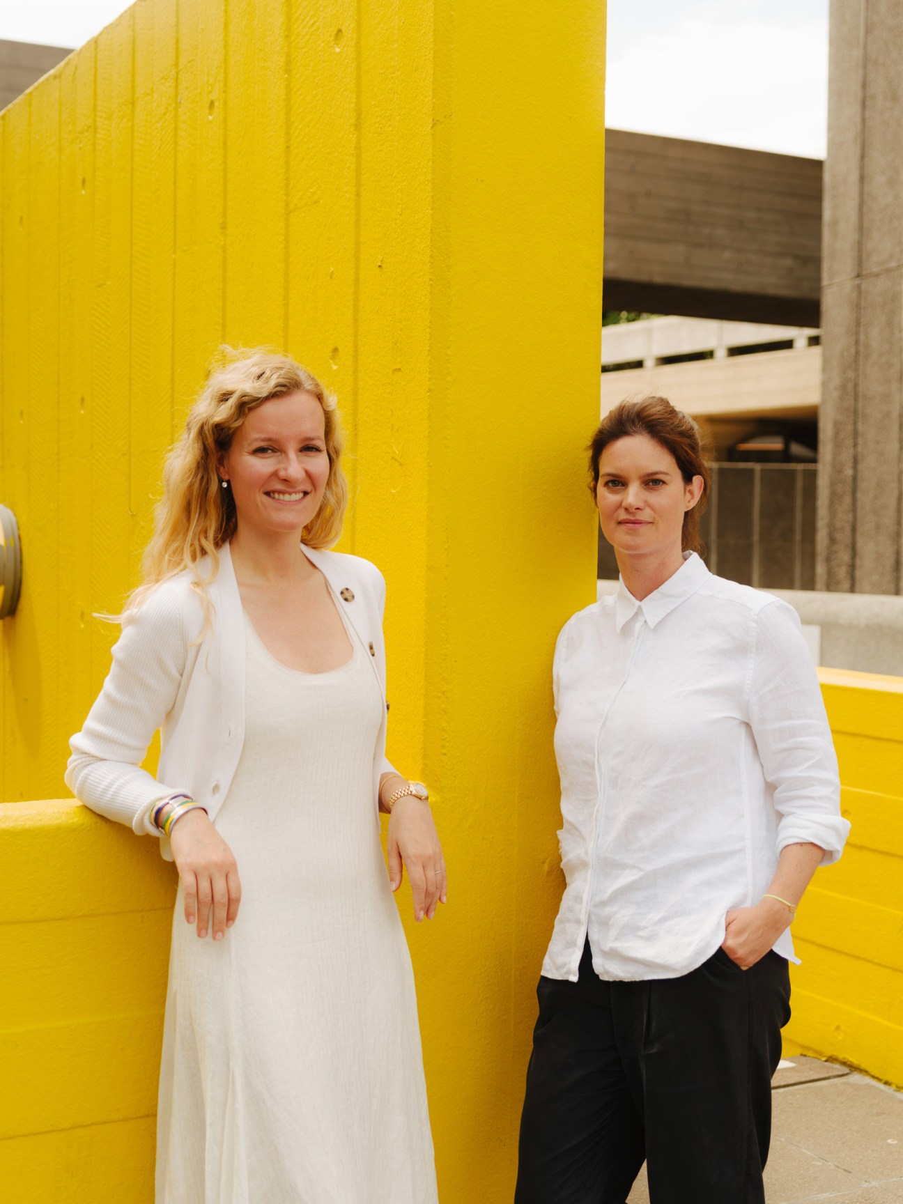 Marlies Verhoeven and Daisy Peat, co-founders of The Cultivist, standing against a bright yellow wall.