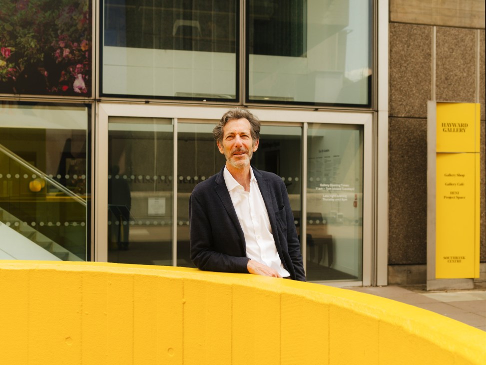 Ralph Rugoff, director of Hayward Gallery, standing outside the gallery entrance with yellow signage.