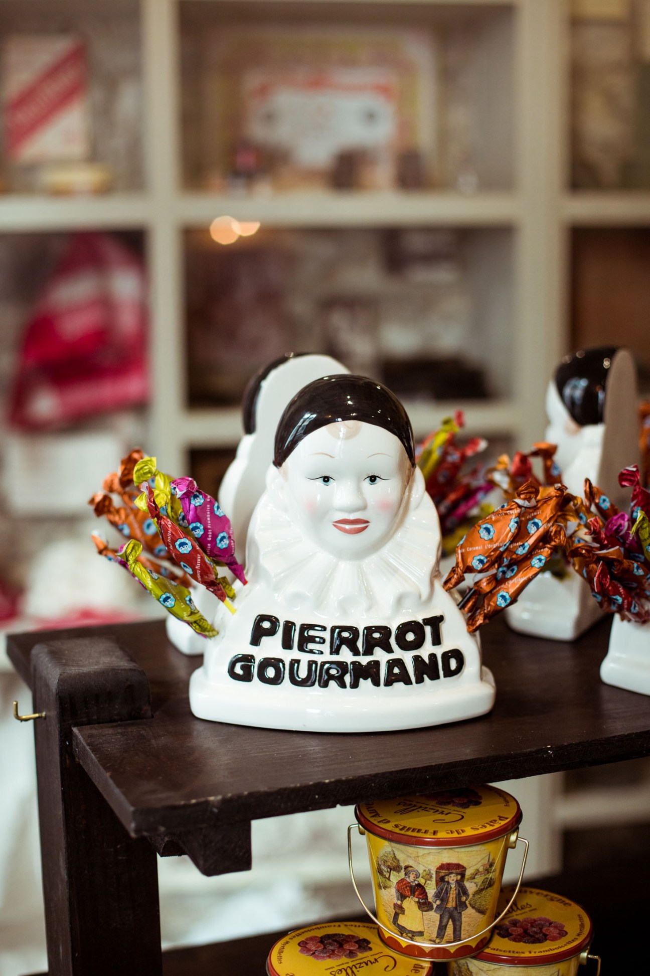 Ceramic Pierrot Gourmand figurine with colorful fabric wings displayed in Maison Empereur shop.