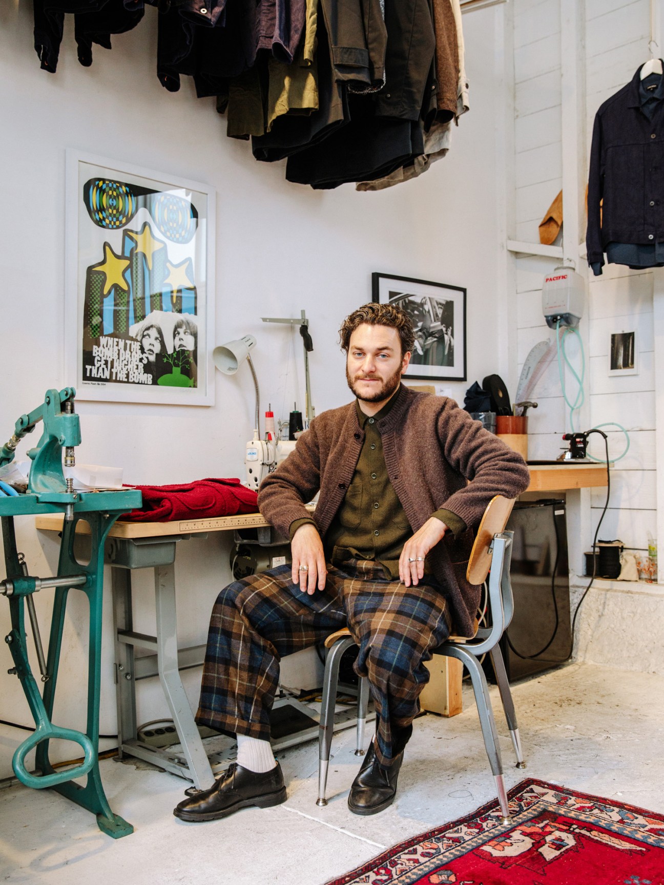 Man sitting in a studio workspace wearing Cinoh coat and jumper, Massimo Alba shirt, and Jacob Cohën jeans.