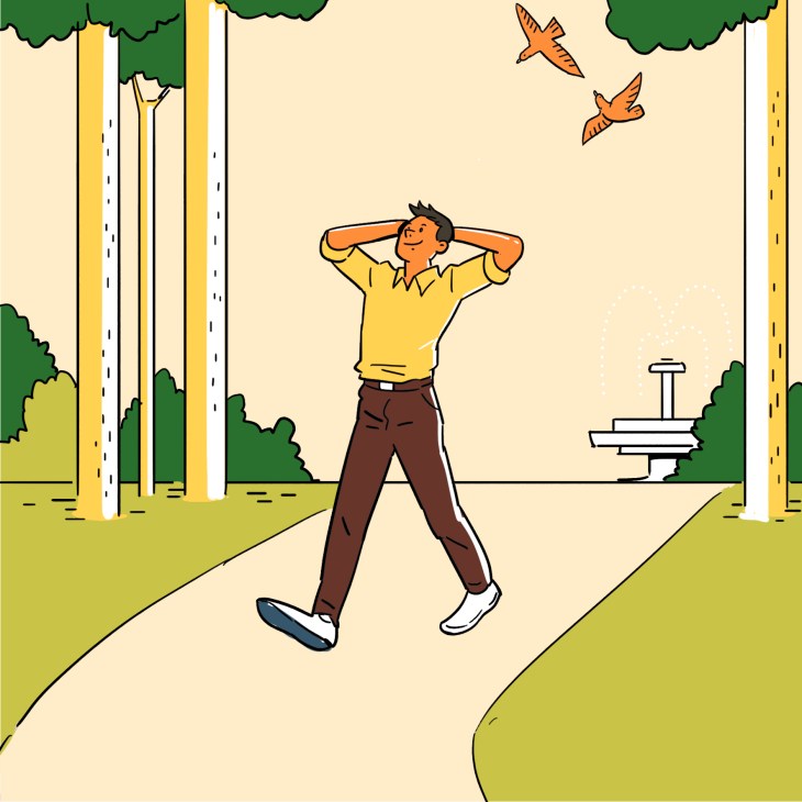 Man relaxing in a park with hands behind head, wearing yellow shirt and brown pants.