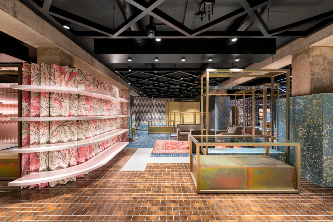 Interior of Flannels luxury department store on Oxford Street featuring red patterned wall displays, brass-framed display cases, and modern ceiling fixtures.