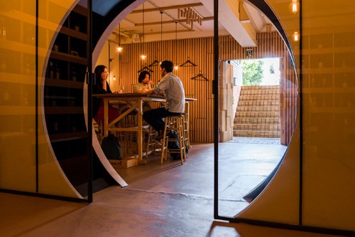 Interior view of Wineshop Flow in Tokyo, showing customers at a wooden bar counter through circular doorway.
