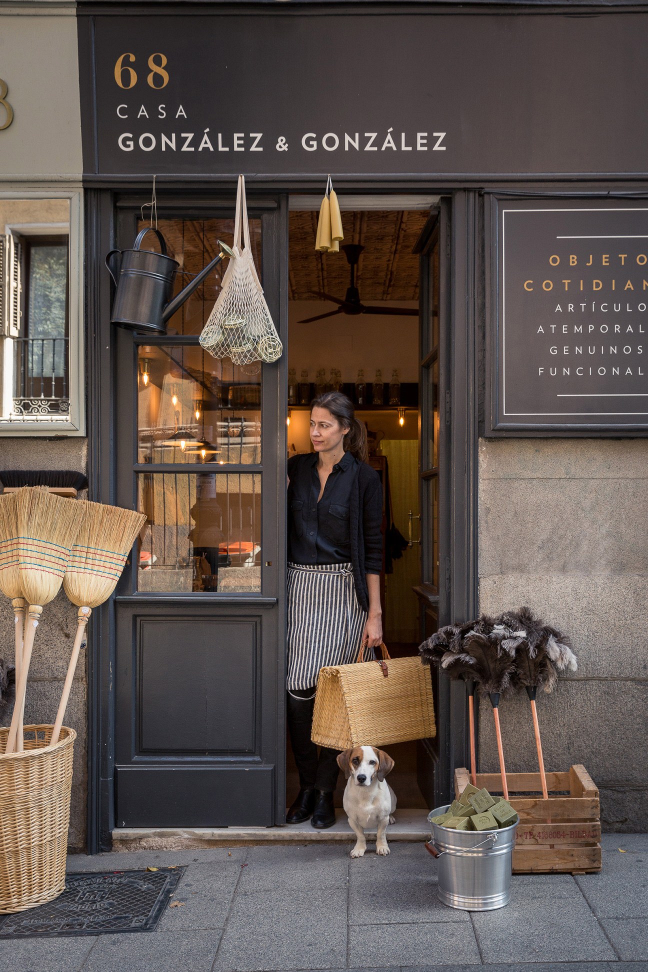 Woman stands in doorway of Casa González & González homeware shop in Madrid, holding a woven basket.