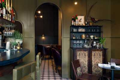 Interior of Garden & Gun Club in Atlanta showing bar counter, shelving, and dining area with warm lighting.