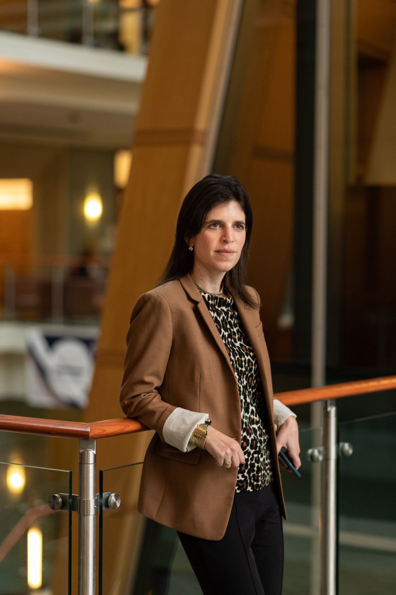Women in a blazer leaning against a railing