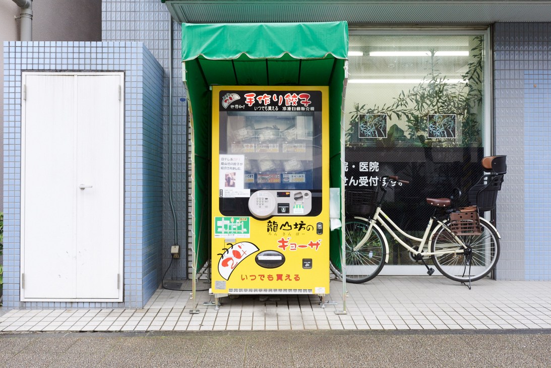 Japanese vending machine dispensing gyoza dumplings and other products on a city street.