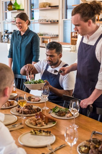 Staff members serve food during a communal meal at Agrarian Kitchen Eatery in Hobart.
