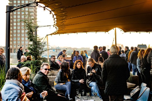 Diners enjoying drinks and conversation on a covered waterfront terrace at Søholm restaurant in Tokyo.