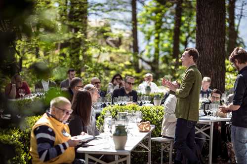Guests dine at long tables outdoors among trees at the Lageder winery's Summa wine fair event.