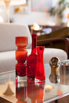 Red decorative glass vessels and bottles arranged on a table in a modern interior space.