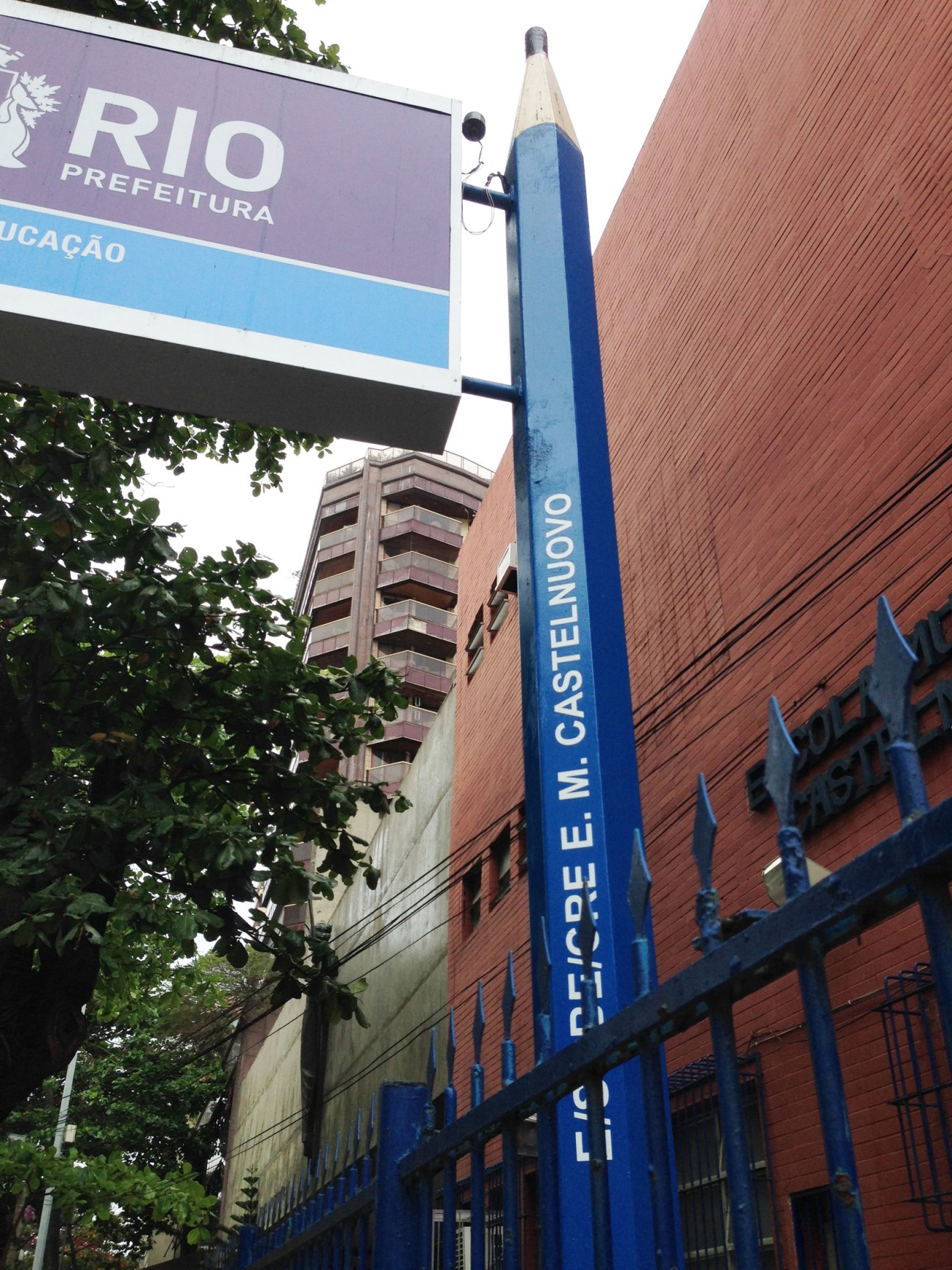Giant pencil-shaped bollard street furniture with blue base and white tip on Rio de Janeiro pavement.