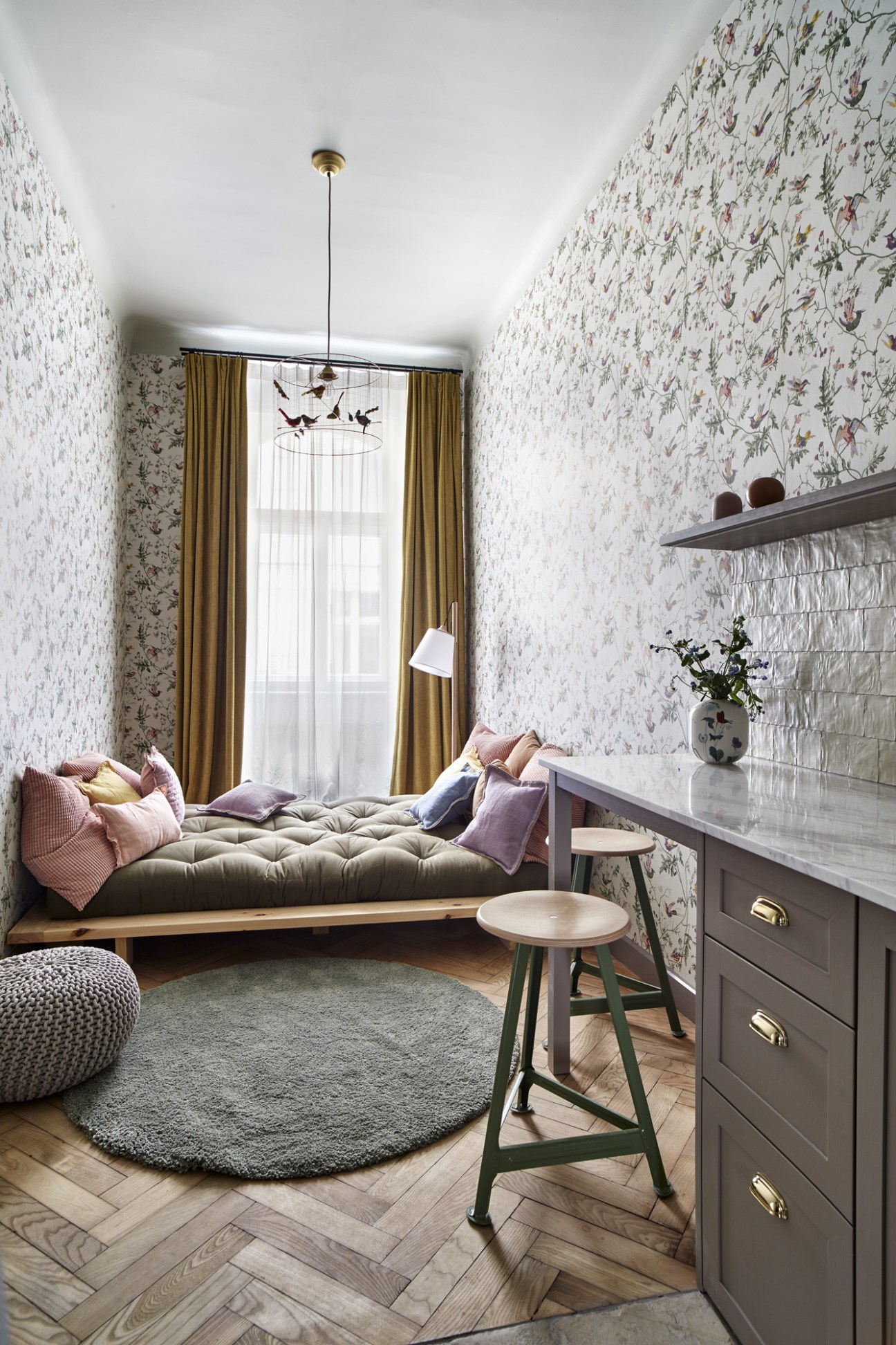 Modern hotel room with floral wallpaper, window seat with cushions, and minimal furnishings