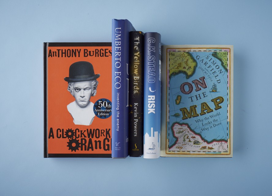 A selection of books displayed against a light blue background, including A Clockwork Orange, Umberto Eco's Inventing the Enemy, and Simon Garfield's On the Map.