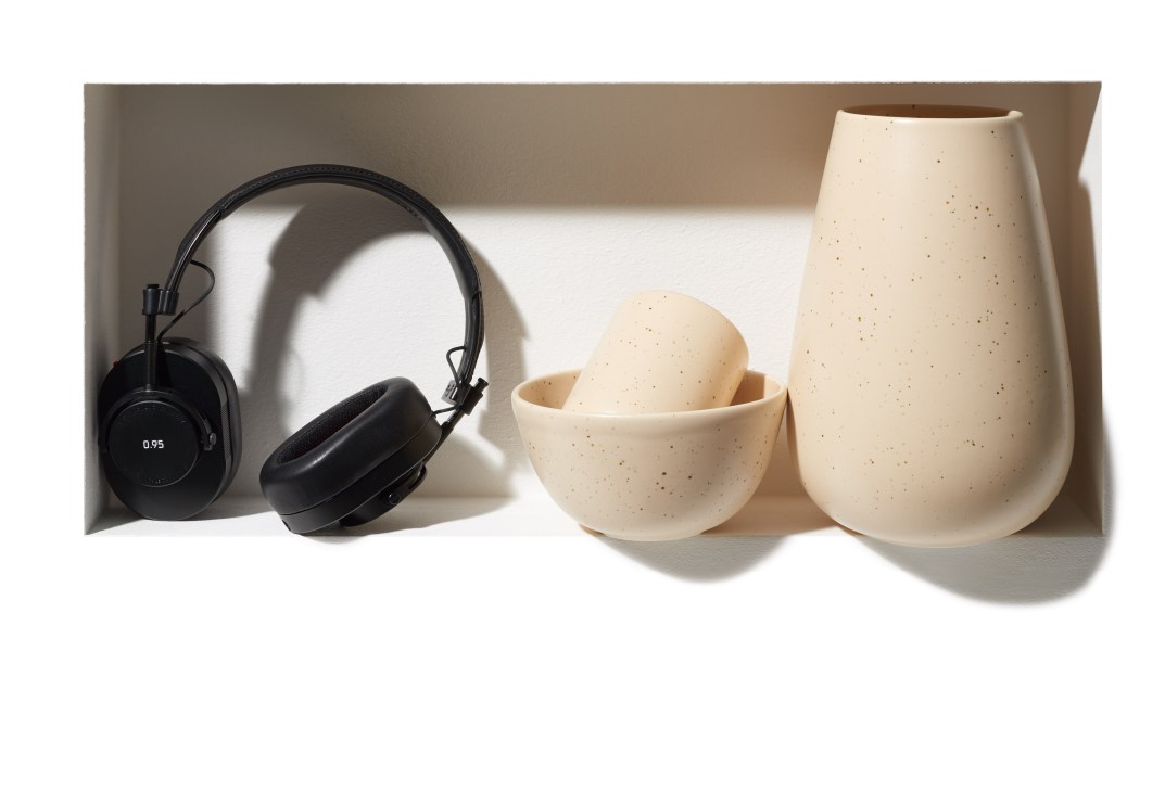Black over-ear headphones and cream ceramic vessels with speckled glaze displayed in white box.
