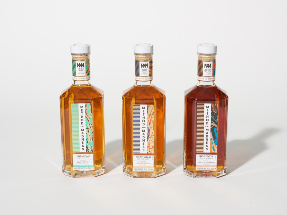 Three bottles of Method and Madness Irish whiskey with colorful labels displayed against a white background.