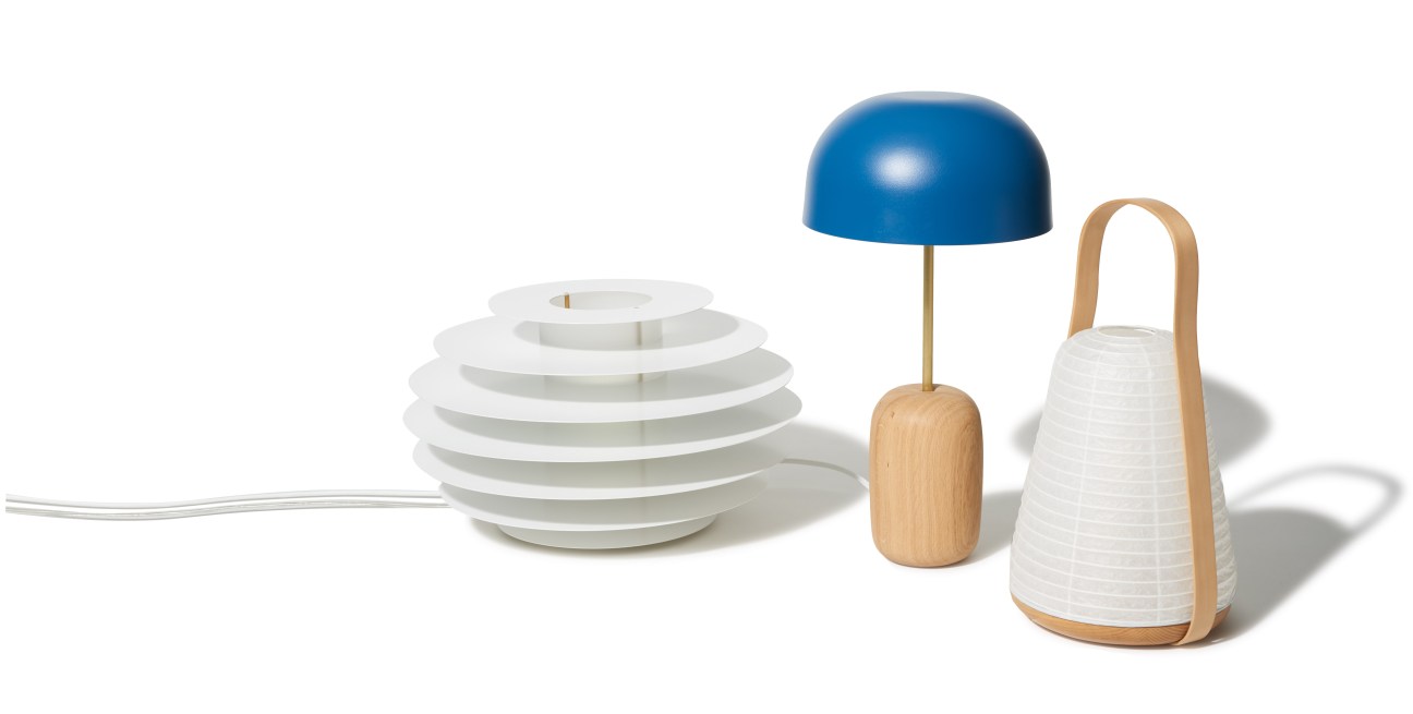 White washi paper lantern with wooden handle alongside a blue dome lamp and white ridged pendant light.
