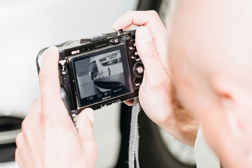 Hands holding a black vintage camera displaying a black-and-white photograph on its screen.