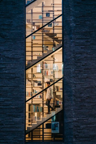 Narrow staircase with bookshelves connects multiple floors in Rainbow Publishing's Seoul office building.