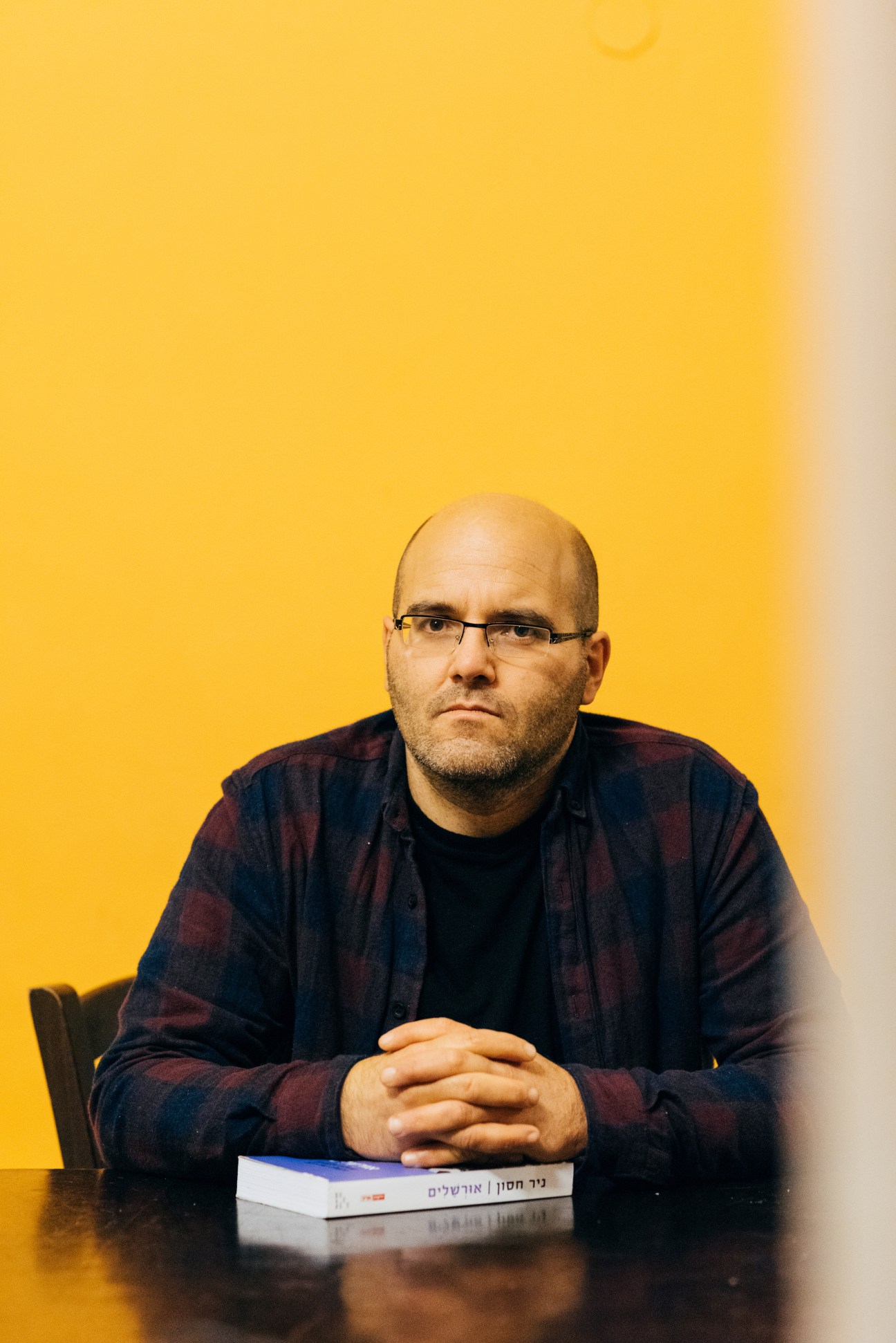 Nir Hasson, Jerusalem correspondent for Haaretz newspaper, seated at a table against a yellow background.