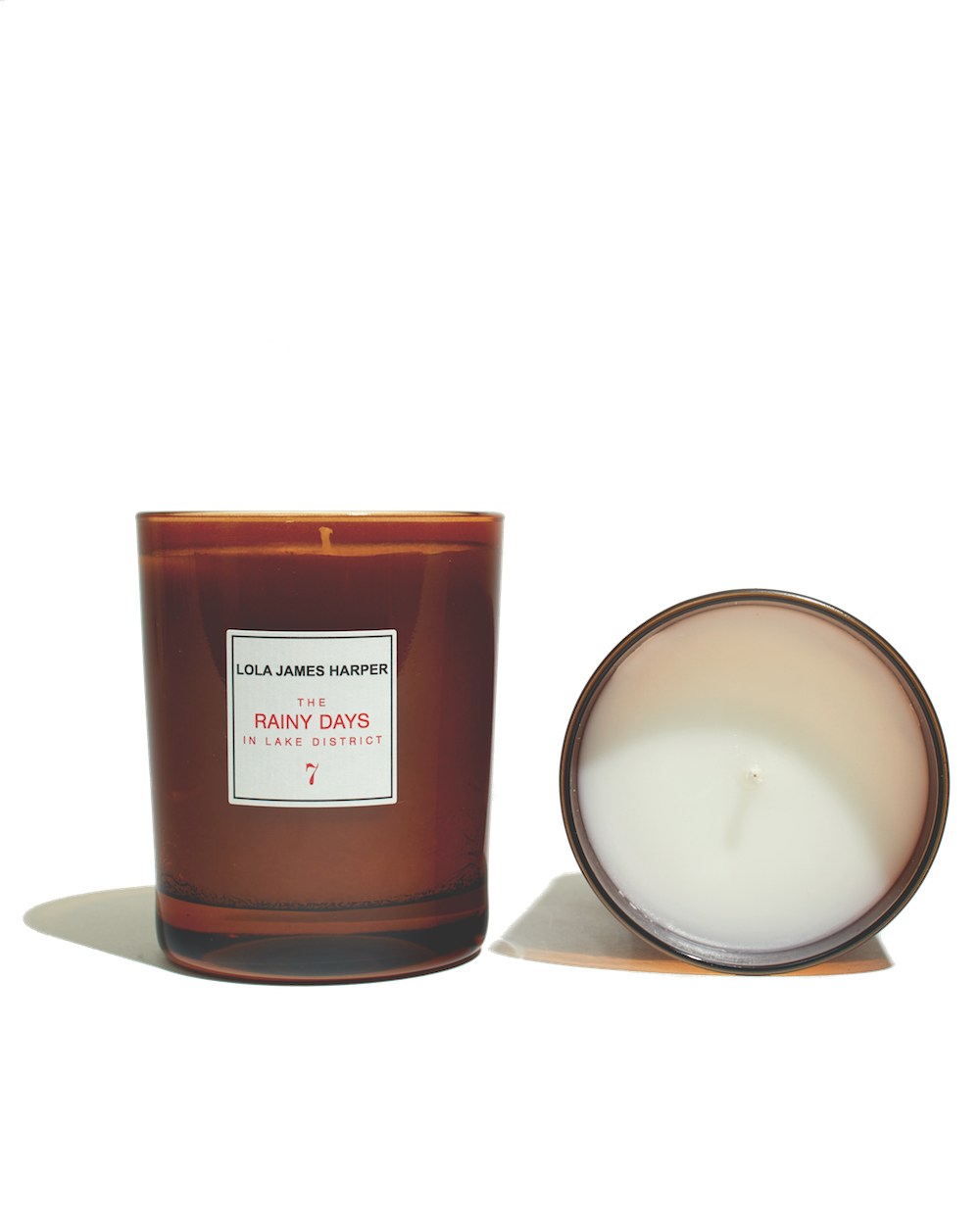Lola James Harper scented candle in amber glass with cream-colored wax, shown with lid removed.