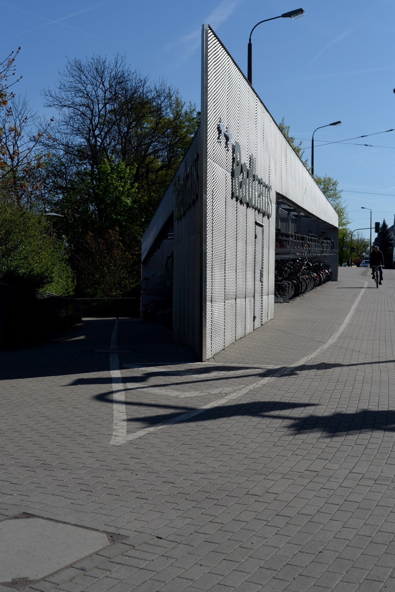 Modern triangular bicycle station with perforated metal facade and bike storage at Erfurt train station, Germany.