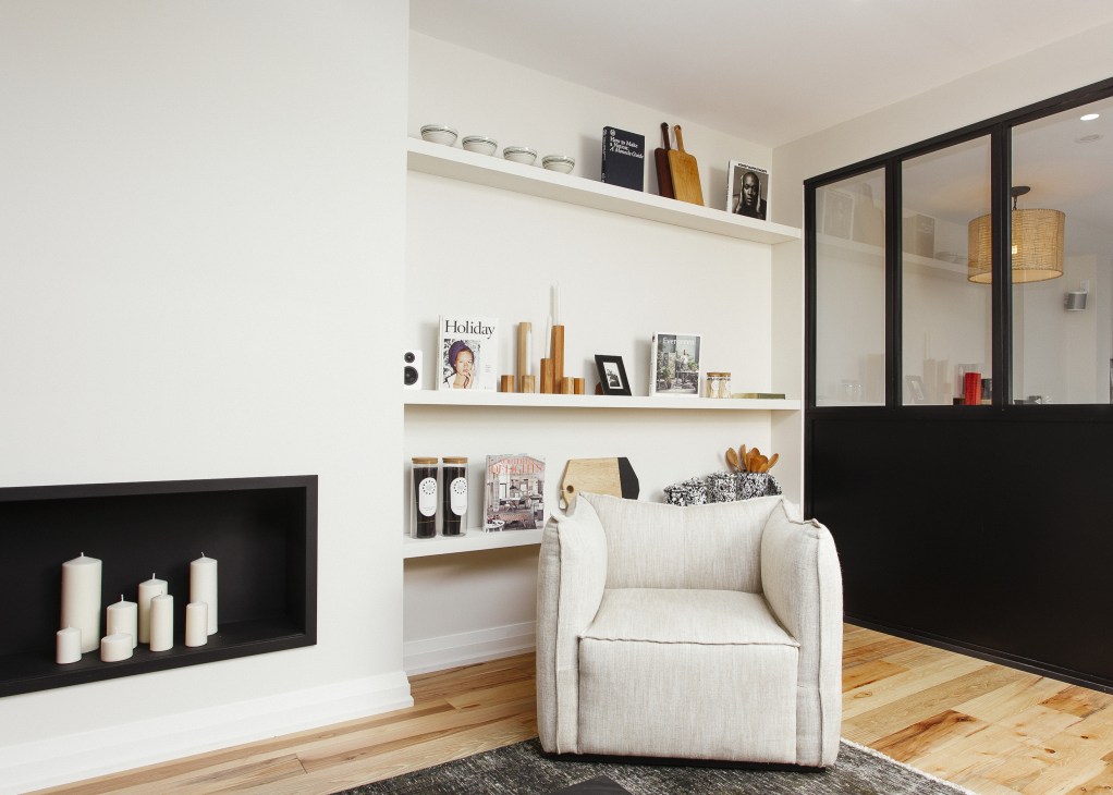 Interior of KOTN retail store in Toronto featuring white shelving, wooden utensils, magazines, and a cream-colored armchair.