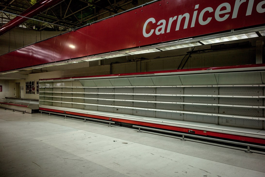 Empty supermarket shelves in the meat section with bare white shelving units