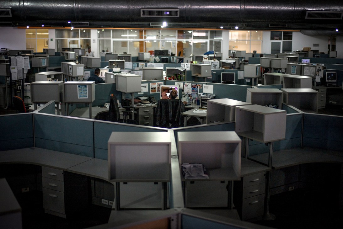 Empty office cubicles with computer monitors in a newsroom workspace