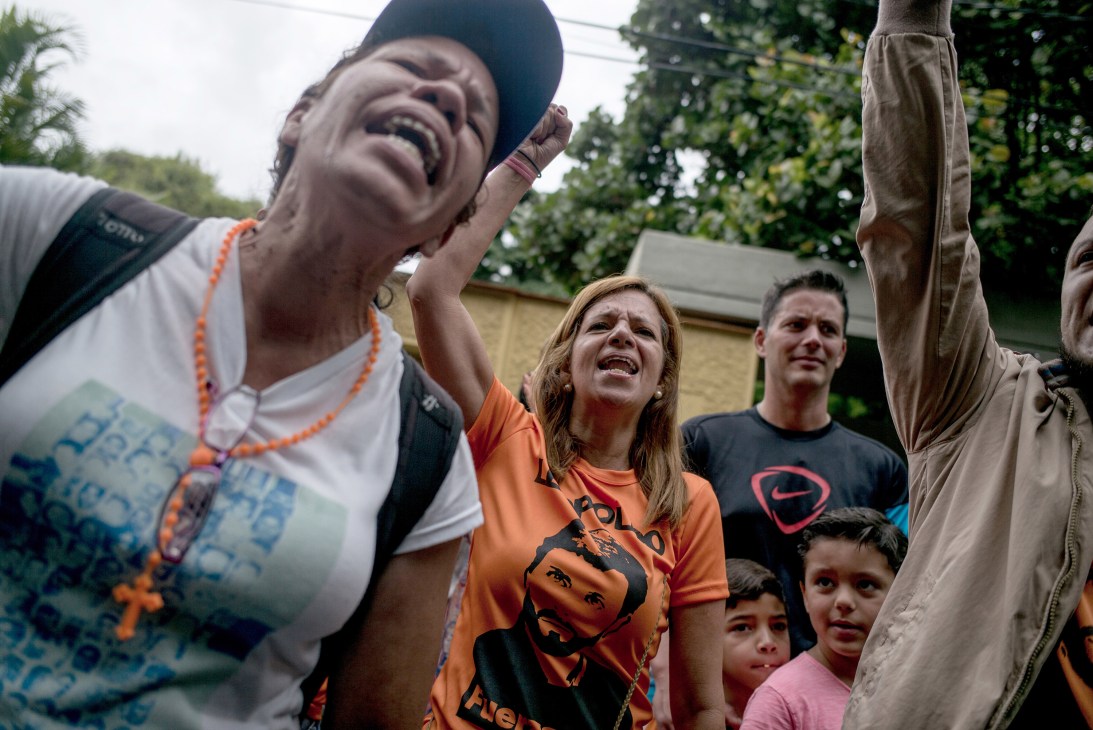Supporters celebrate with raised hands and emotional expressions outdoors