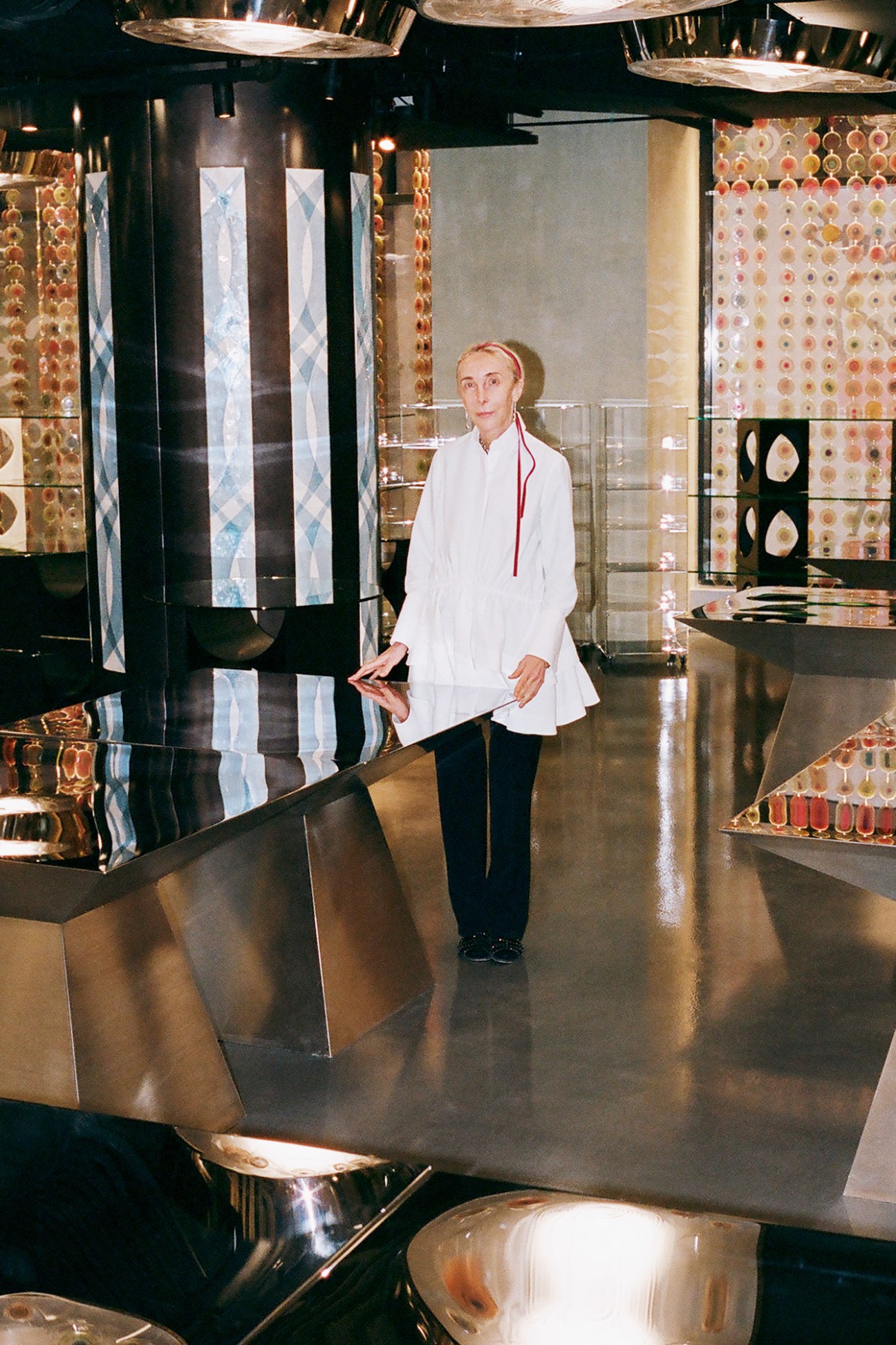 Woman in white button-up shirt standing in modern retail space with colorful textile displays on walls.