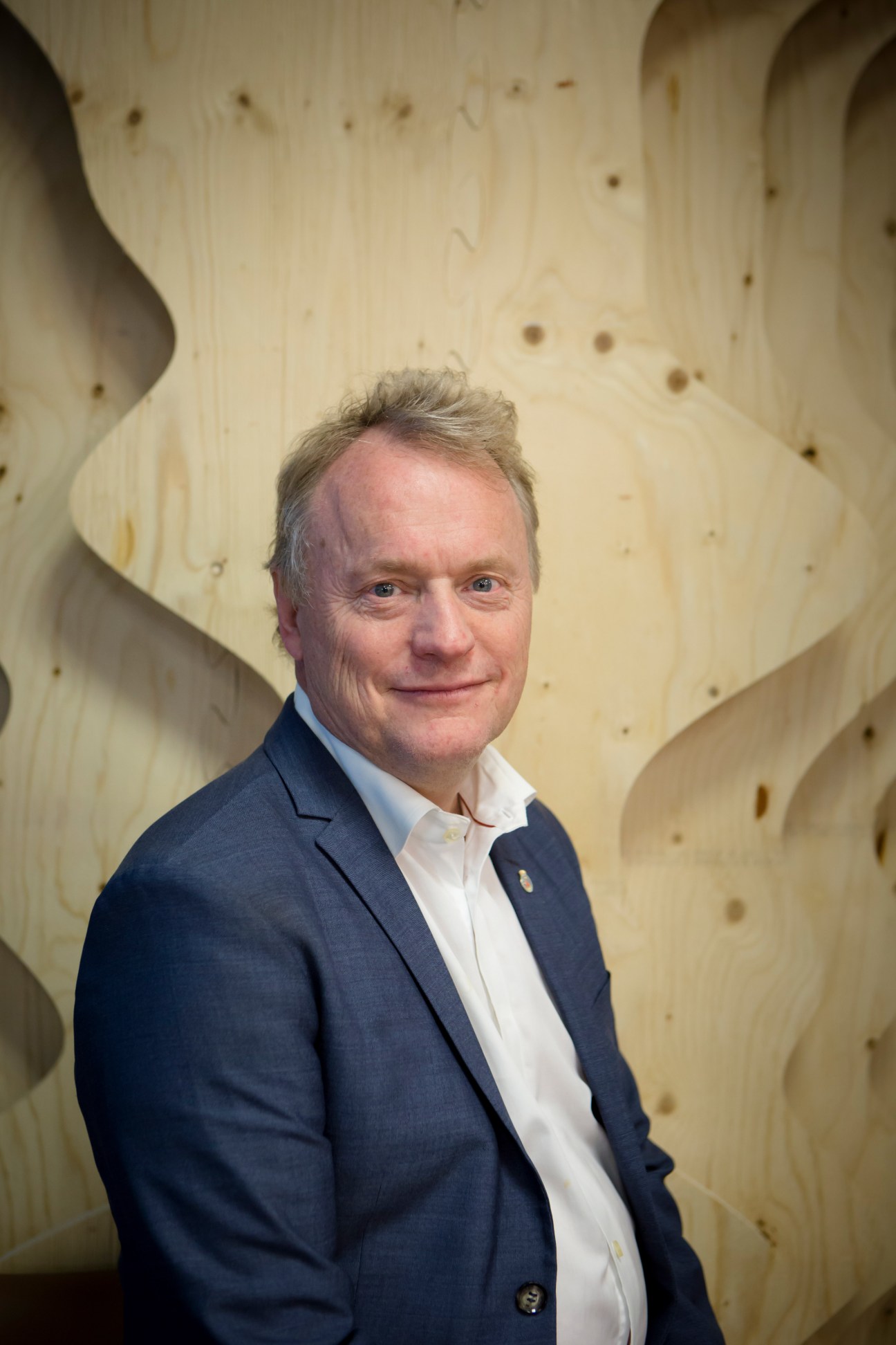 Raymond Johansen, governing mayor of Oslo, poses for a portrait against a textured light wood background.