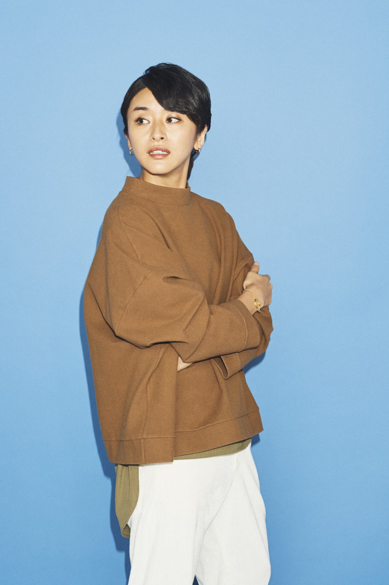 Person wearing a tan pullover and shirt against a blue background.