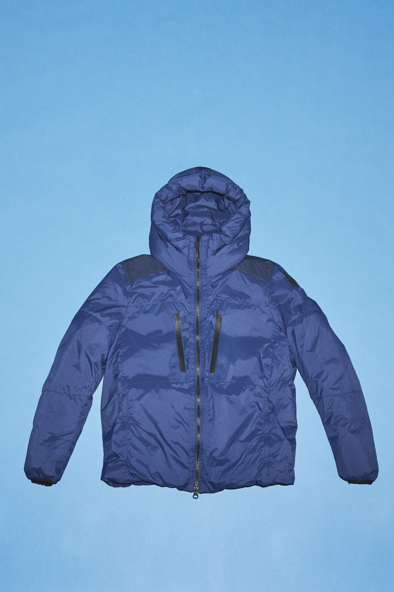 Navy blue puffer jacket with hood against clear blue background.