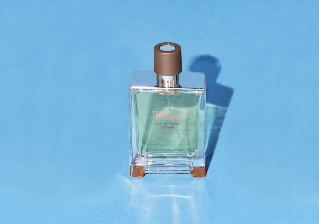 Hermès Terre d'Hermès Eau Intense Vétiver fragrance bottle with brown cap on blue background.