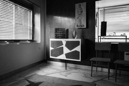 Minimalist black and white interior with geometric patterned cabinet and mid-century furniture.