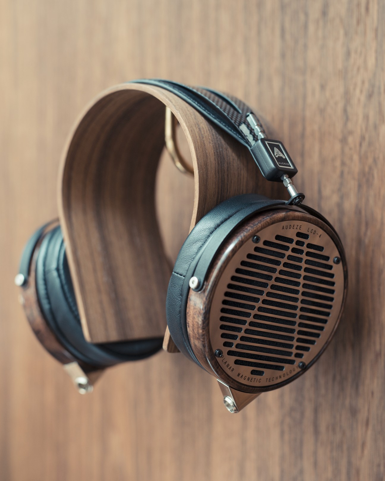 Audeze LCD-4 headphones with wood-paneled earcups and leather headband displayed against a wooden background.