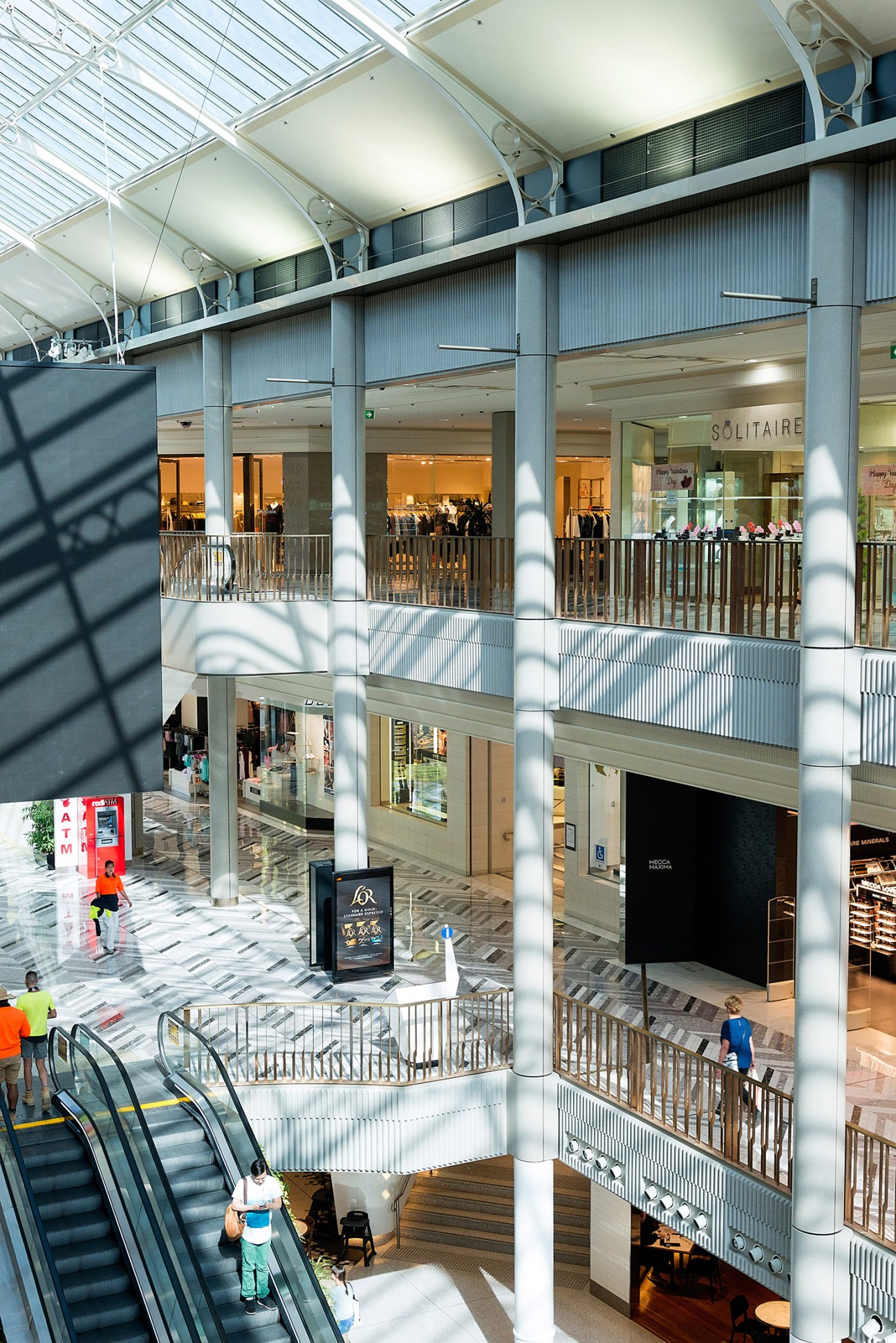 Interior of Canberra Centre shopping mall with multiple levels, natural lighting, escalators, and retail storefronts.