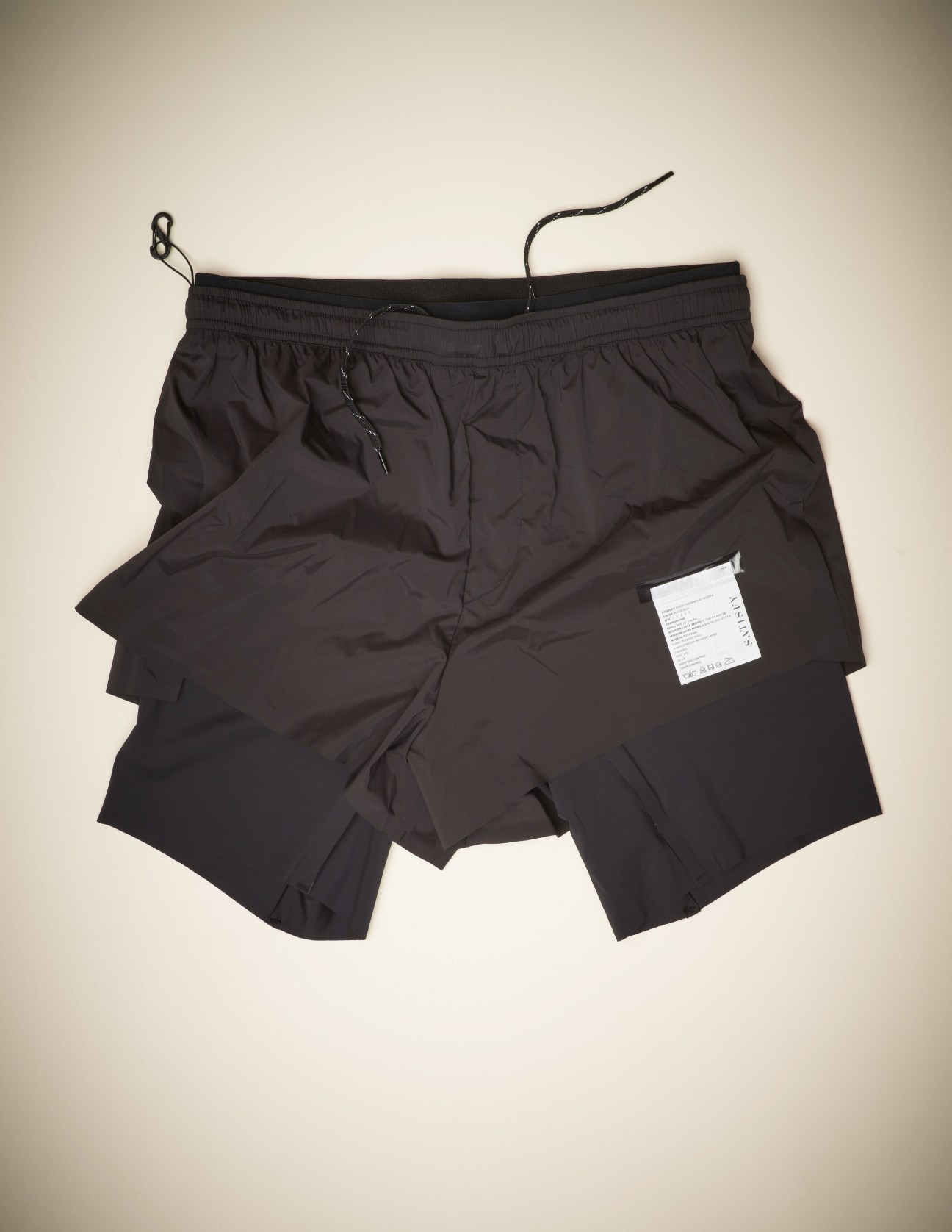 Black athletic shorts with drawstring and care label, laid flat against neutral background.