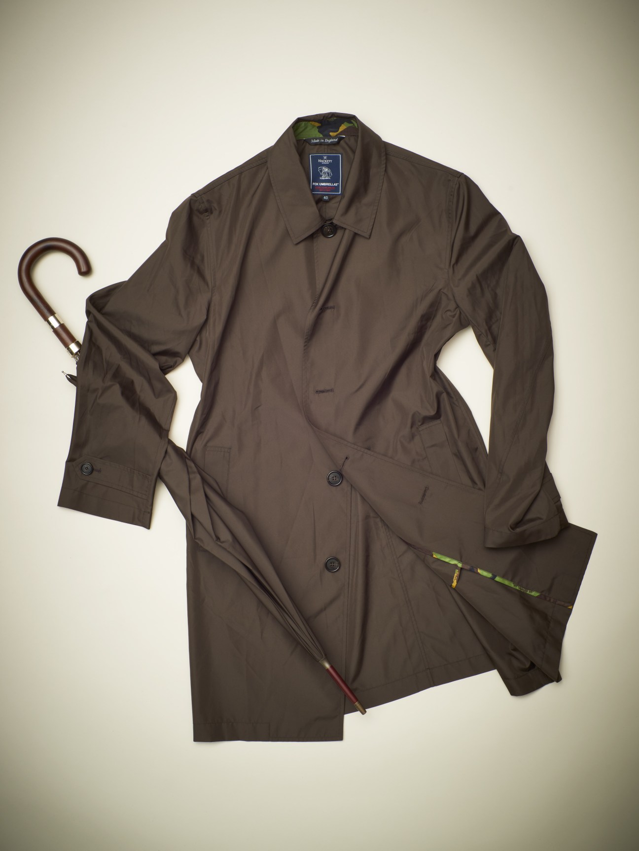 Brown mac raincoat with matching umbrella displayed flat on neutral background.