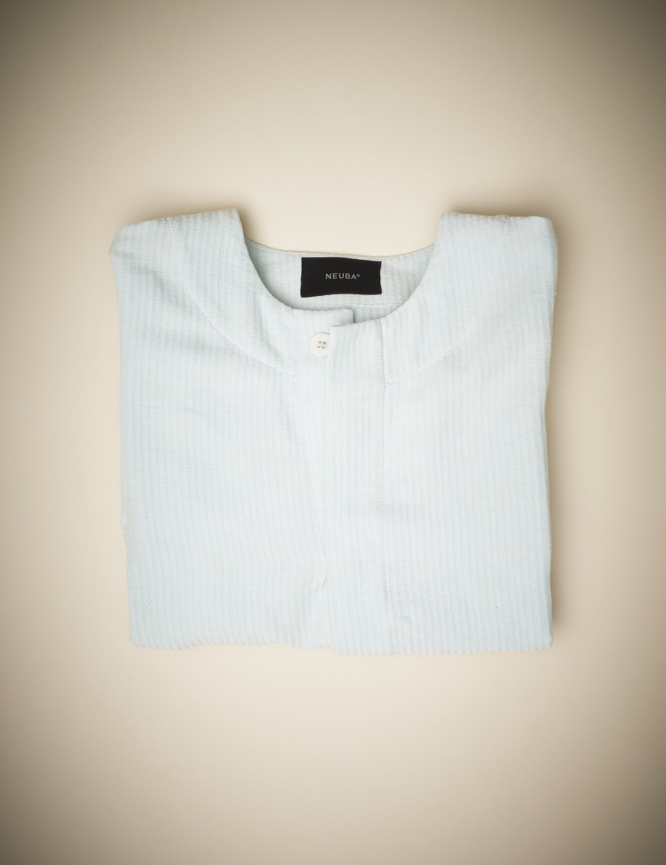 White hand-woven textured shirt with Neuba label displayed flat on neutral background.