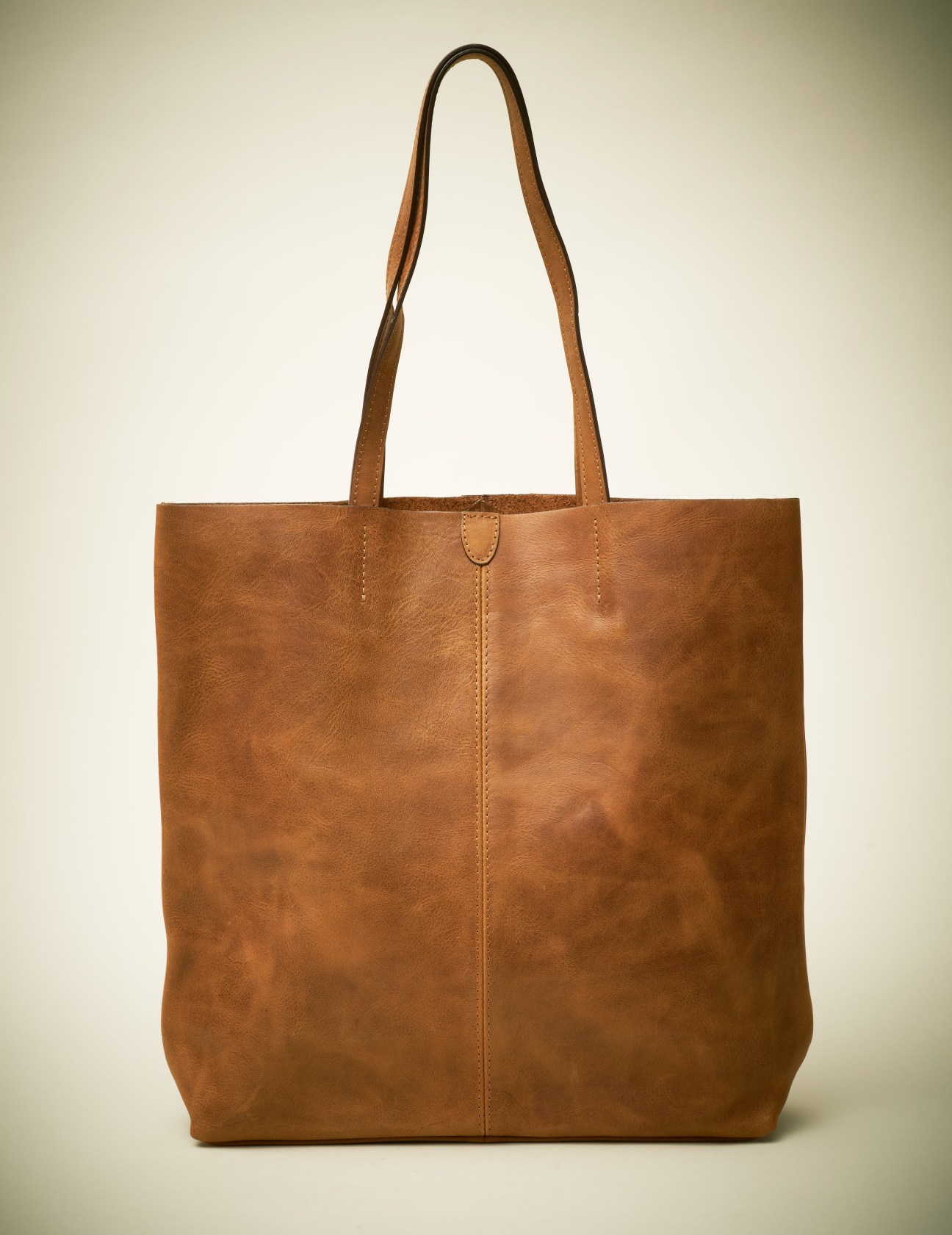 Brown leather tote bag with long handles and center seam detail.