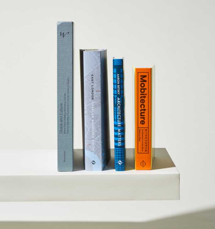 Four architecture and design books displayed standing upright on a white surface.