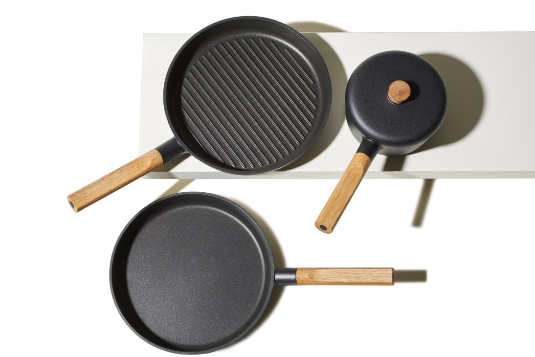 Eva Solo Nordic Kitchen pots and pans with light aluminium construction and honey-hued oak handles.