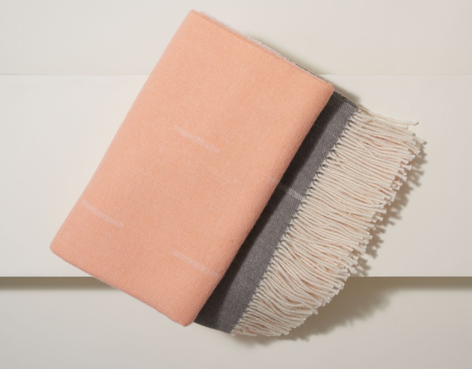 Folded blanket in peachy-pink and cream with fringe edges, designed by Note Design Studio and Fogia.