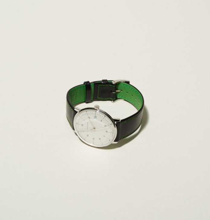 Junghans watch with white dial, silver hands, black leather strap with green interior detail.